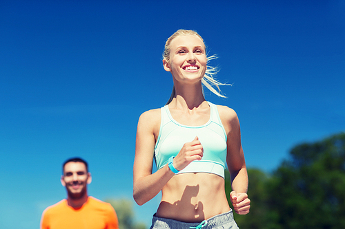 fitness, sport, friendship and healthy lifestyle concept - smiling couple running outdoors