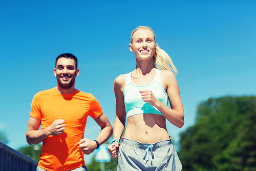 fitness, sport, friendship and healthy lifestyle concept - smiling couple running outdoors