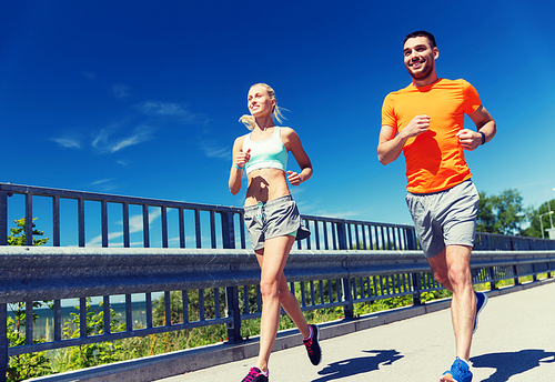 fitness, sport, friendship and healthy lifestyle concept - smiling couple running at summer seaside