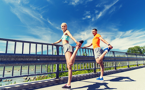 fitness, sport, training and lifestyle concept - smiling couple stretching outdoors