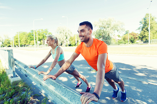 fitness, sport, training and healthy lifestyle concept - close up of happy couple doing push-ups outdoors