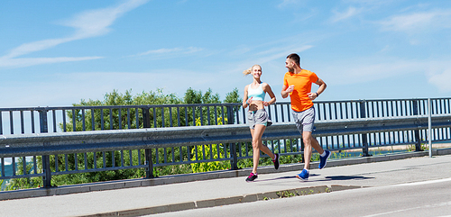 fitness, sport, friendship and healthy lifestyle concept - smiling couple running at summer seaside