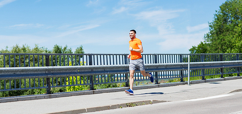 fitness, sport, people, technology and healthy lifestyle concept - smiling young man with heart rate watch running at summer seaside