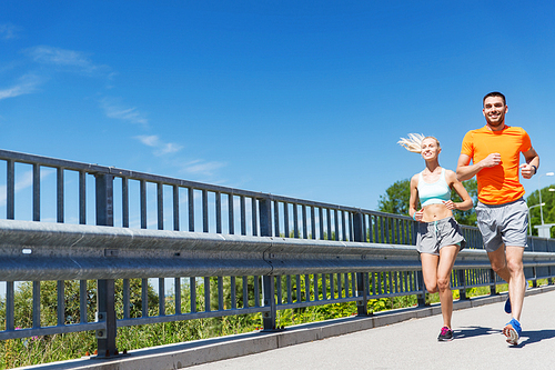 fitness, sport, friendship and healthy lifestyle concept - smiling couple running at summer seaside