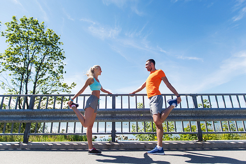 fitness, sport, training and lifestyle concept - smiling couple stretching outdoors