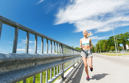 fitness, sport, people, technology and healthy lifestyle concept - smiling young woman with heart rate watch running outdoors