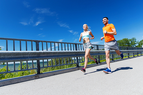 fitness, sport, friendship and healthy lifestyle concept - smiling couple with heart-rate watch running at summer seaside