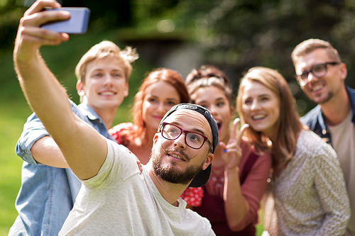 leisure, holidays, reunion, people and friendship concept - happy teenage friends taking selfie by smartphone at summer
