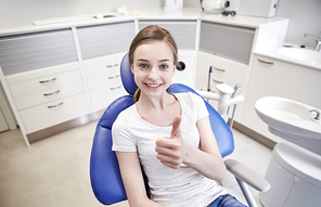 people, medicine, stomatology and health care concept - happy patient girl showing thumbs up at dental clinic office