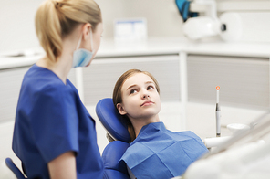 people, medicine, stomatology and health care concept - happy female dentist with patient girl talking at dental clinic office