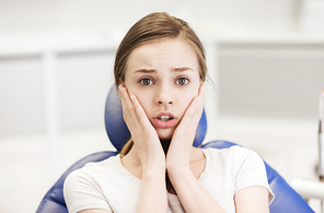 people, medicine, stomatology and phobia concept - scared and terrified patient girl at dental clinic office