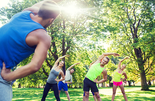 fitness, sport, friendship and healthy lifestyle concept - group of happy teenage friends or sportsmen exercising and stretching hands at boot camp