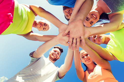 fitness, sport, friendship and healthy lifestyle concept - group of happy teenage friends with hands on top outdoors