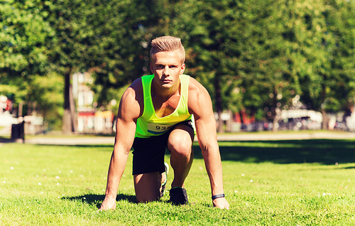 fitness, sport, marathon and healthy lifestyle concept - young sportsman with badge number on start of race outdoors