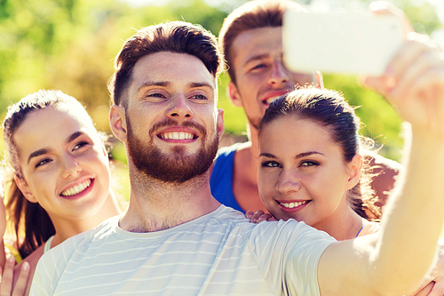 fitness, sport, friendship, technology and healthy lifestyle concept - group of happy teenage friends taking selfie with smartphone outdoors