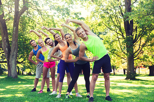 fitness, sport, friendship and healthy lifestyle concept - group of happy teenage friends or sportsmen exercising and stretching hands at boot camp