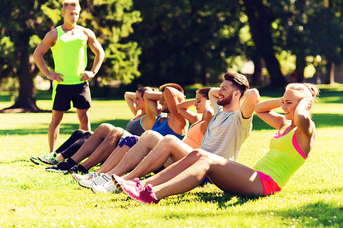 fitness, sport, friendship and healthy lifestyle concept - group of happy teenage friends or sportsmen exercising and doing sit-ups at boot camp