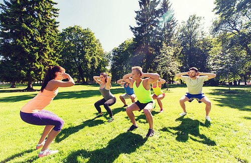 fitness, sport, friendship and healthy lifestyle concept - group of happy teenage friends exercising and doing squats at boot camp