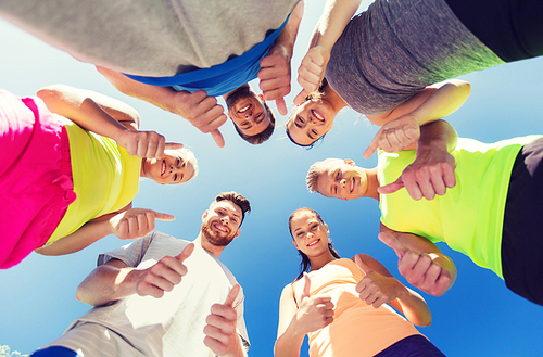 fitness, sport, friendship and healthy lifestyle concept - group of happy teenage friends in circle outdoors showing thumbs up