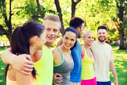 fitness, sport, friendship and healthy lifestyle concept - group of happy teenage friends or sportsmen hugging and talking outdoors