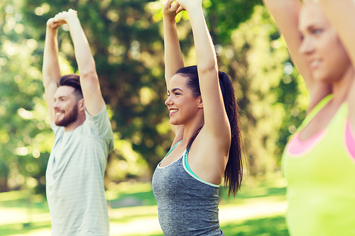 fitness, sport, friendship and healthy lifestyle concept - group of happy teenage friends or sportsmen exercising and stretching hands up at boot camp