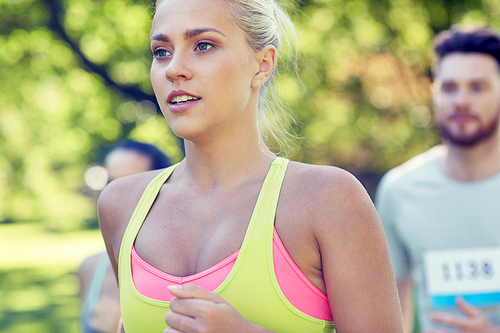 fitness, sport, friendship, race and healthy lifestyle concept - group of happy teenage friends or sportsmen running marathon with badge numbers outdoors