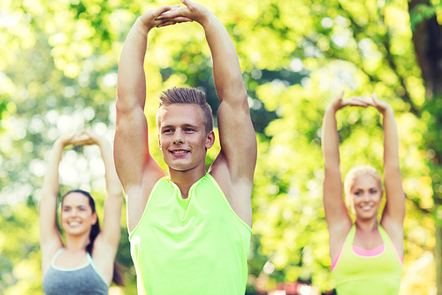 fitness, sport, friendship and healthy lifestyle concept - group of happy teenage friends or sportsmen exercising and stretching hands up at boot camp