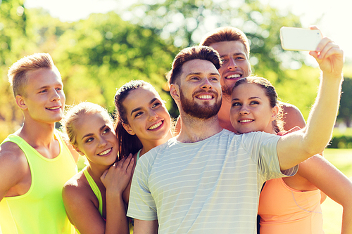 fitness, sport, friendship, technology and healthy lifestyle concept - group of happy teenage friends taking selfie with smartphone outdoors