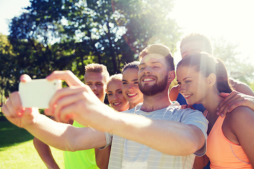 fitness, sport, friendship, technology and healthy lifestyle concept - group of happy teenage friends taking selfie with smartphone outdoors