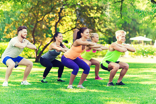 fitness, sport, friendship and healthy lifestyle concept - group of happy teenage friends or sportsmen exercising and doing squats at boot camp