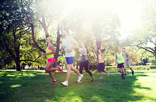 fitness, sport, friendship, race and healthy lifestyle concept - group of happy teenage friends or sportsmen running marathon with badge numbers outdoors