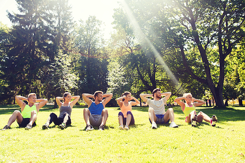 fitness, sport, friendship and healthy lifestyle concept - group of happy teenage friends or sportsmen exercising and doing sit-ups at boot camp