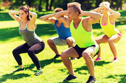 fitness, sport, friendship and healthy lifestyle concept - group of teenage friends or sportsmen exercising and doing squats at boot camp