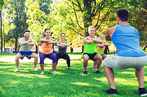 fitness, sport, friendship and healthy lifestyle concept - group of happy teenage friends or sportsmen exercising and doing squats at boot camp