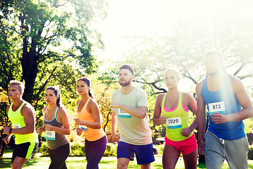 fitness, sport, race and healthy lifestyle concept - group of teenage friends or sportsmen with badge numbers on start of running marathon outdoors