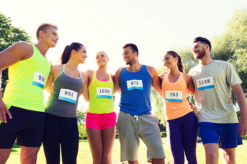 fitness, sport, marathon, friendship and healthy lifestyle concept - group of happy teenage friends or sportsmen couple with racing badge numbers outdoors