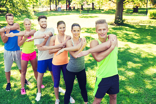 fitness, sport, friendship and healthy lifestyle concept - group of happy teenage friends or sportsmen exercising and stretching hands at boot camp