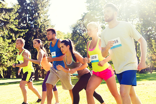 fitness, sport, race and healthy lifestyle concept - group of teenage friends or sportsmen with badge numbers on start of running marathon outdoors