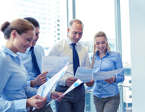 business, teamwork, people and technology concept - smiling business team with papers meeting in office