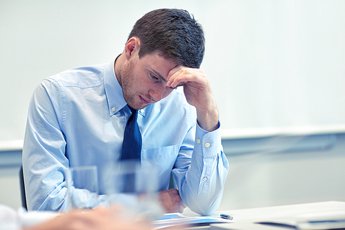 business, people and crisis concept - businessman sitting sad and solving problem in office