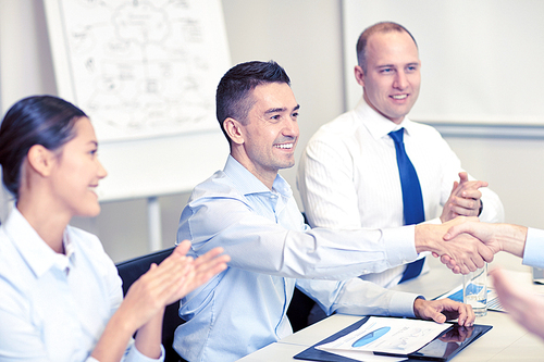 business, people and partnership concept - smiling business team shaking hands and applauding in office