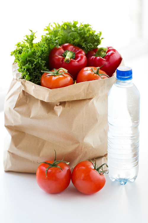 cooking, , vegetarian food and healthy eating concept - close up of paper bag with fresh ripe juicy vegetables and water bottle on kitchen table at home