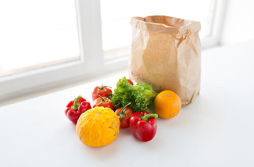 cooking, , vegetarian food and healthy eating concept - close up of paper bag with fresh ripe juicy vegetables, greens and fruits on kitchen table at home