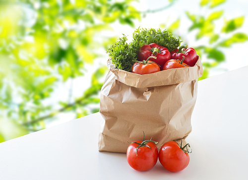 cooking, , vegetarian food and healthy eating concept - paper bag with fresh ripe juicy vegetables and greens on table over green natural background