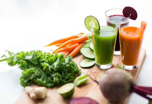 healthy eating, drinks, diet and detox concept - glasses with vegetable fresh juices and food on table