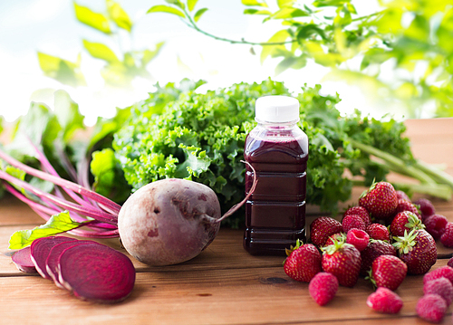 healthy eating, food, ing and vegetarian concept - bottle with beetroot juice, fruits and vegetables on wooden table over green natural background