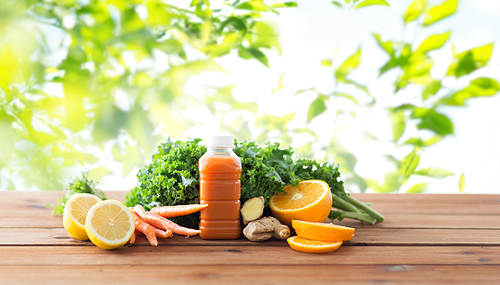 healthy eating, food, dieting and vegetarian concept - bottle with carrot juice, fruits and vegetables on wooden table over green natural background