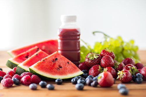 healthy eating, food, dieting and vegetarian concept - bottle with fruit and berry juice or smoothie on wooden table