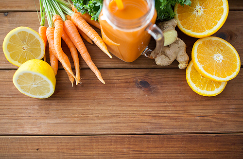 healthy eating, food, dieting and vegetarian concept - glass jug of carrot juice, fruits and vegetables on wooden table