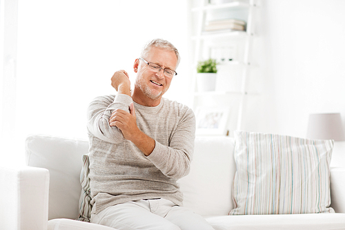 people, healthcare and problem concept - unhappy senior man suffering from elbow pain at home